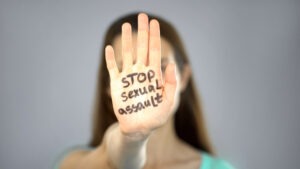 woman-holding-up-palm-that-reads-stop-sexual-assault-Michigan-State