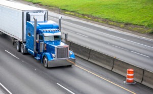 blue big rig tractor trailer drives on freeway in detroit