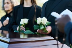 people putting white roses on coffin in dearborn